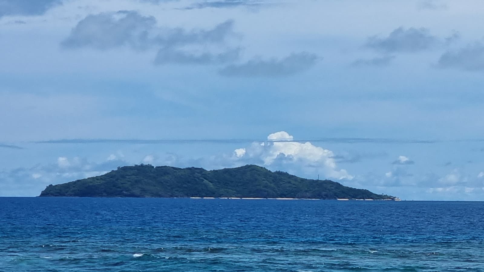 The green hill of Qalito, the island of Castaway Island resort, seen across the sea