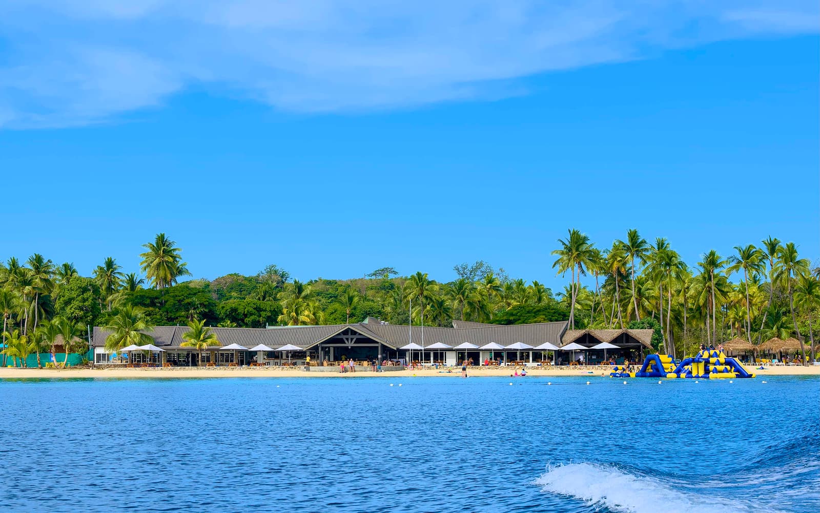 Plantation Island Resort on Malolo Lailai seen from the lagoon, with palms along the beach