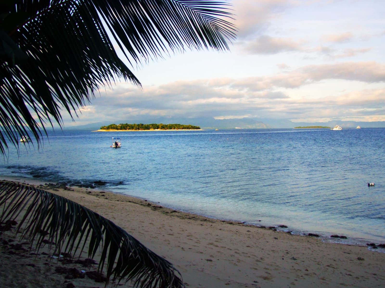 A palm-fringed Mamanuca beach looking across the lagoon to a low coral island